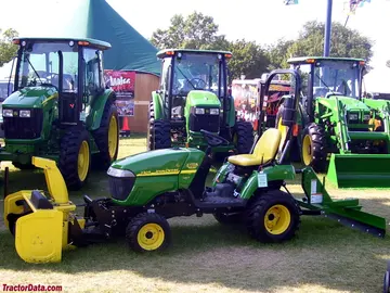 John Deere 2305 mit Schneepflug und Heckmesser, linke Seite.